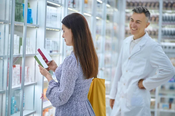 Женщина-клиент выбирает продукты в аптеке — стоковое фото