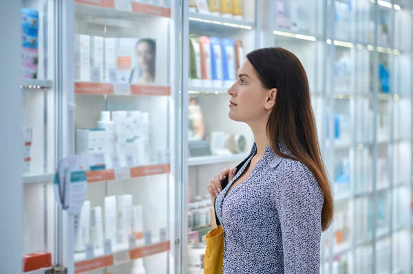 Cliente femenino eligiendo productos en una farmacia —  Fotos de Stock