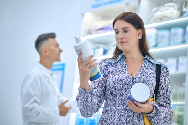 Красивая женщина выбирает продукты по уходу за телом в аптеке — стоковое фото