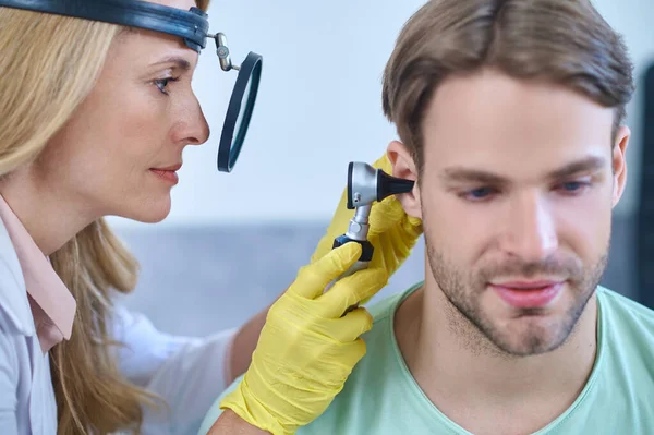 Žena s otoskopem zkoumá mužské ucho — Stock fotografie