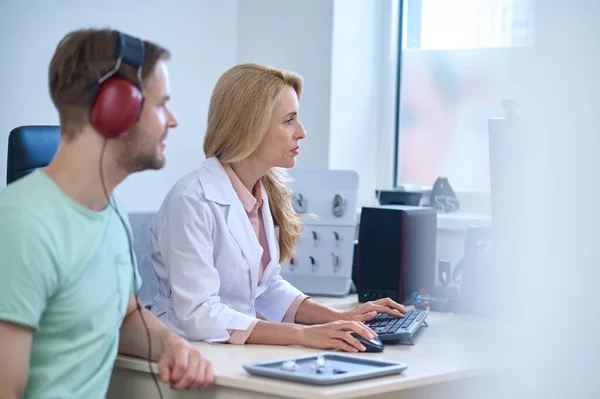 Perfil del hombre en auriculares y de la mujer en el ordenador —  Fotos de Stock