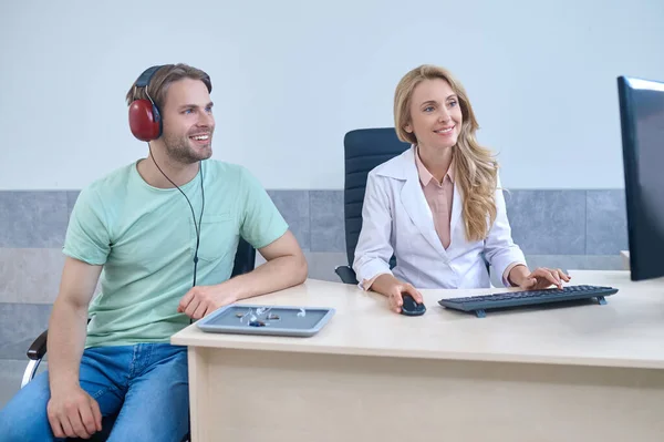 Hombre en auriculares y mujer sentado mirando el ordenador —  Fotos de Stock
