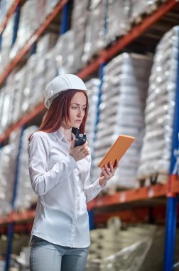 Tablete bakan bir kadın telsizle bilgi konuşuyor.