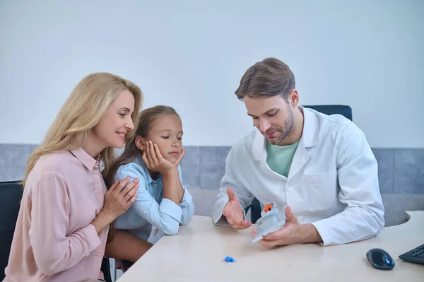 Man showing ear model to girl and woman — Stock Photo, Image