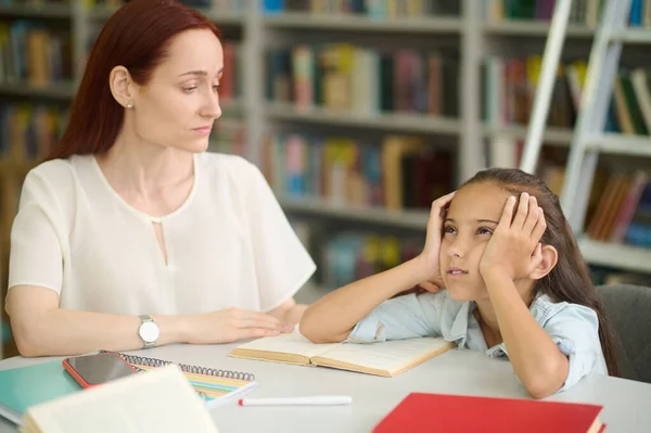 Sad girl and young woman studying at table — Stockfoto