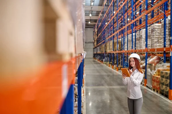 Vrouw met tablet op zoek naar lading in magazijn — Stockfoto