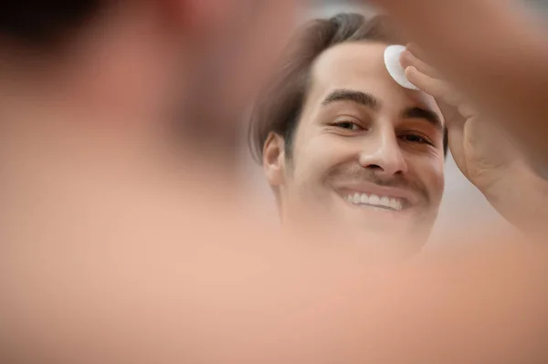 Handsome man cleansing his face with a sponge — Stock Photo, Image