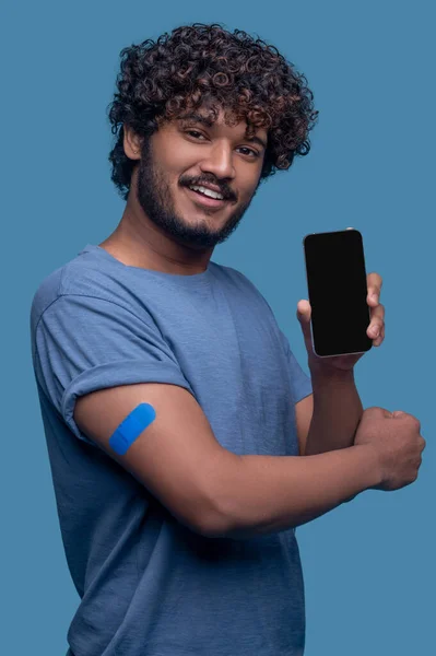予防接種後のカメラで笑顔スマートフォンを持つ男性 — ストック写真