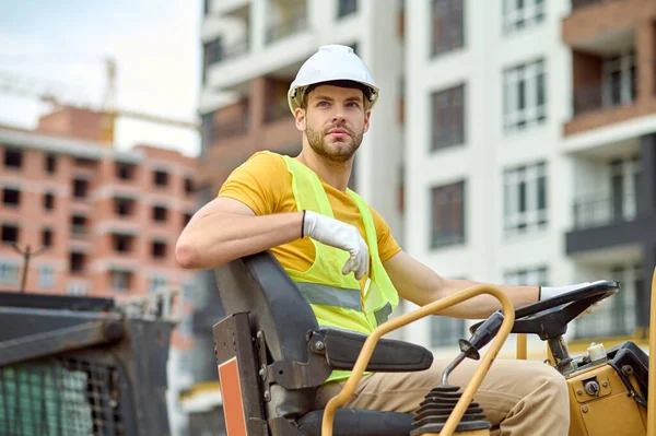 Hombre pensativo conduciendo excavadora en el sitio de construcción —  Fotos de Stock