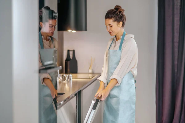 Ama de casa en delantal llenando el lavavajillas — Foto de Stock