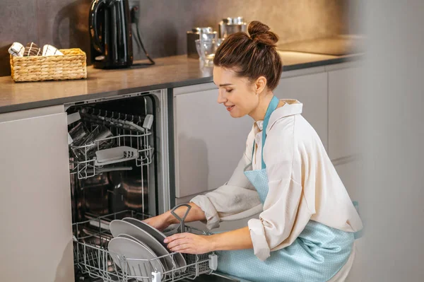 Домогосподарка миє тарілки в посудомийній машині — стокове фото