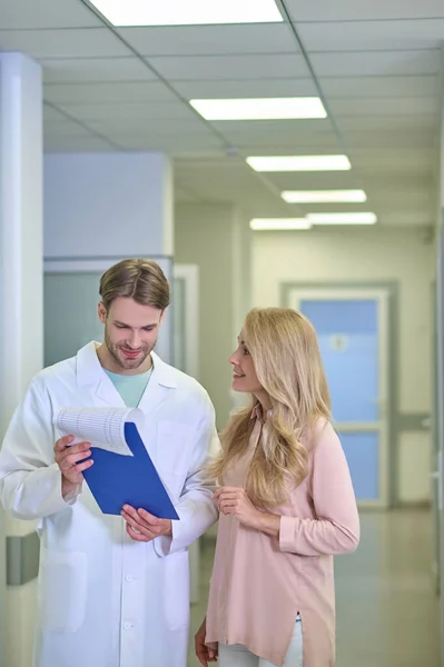 Vrouw kijkt naar man in witte jas toont document — Stockfoto