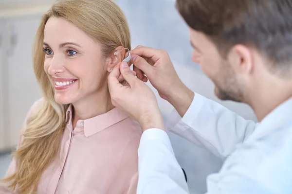Man putting hearing aid on womans ear — Stock Photo, Image