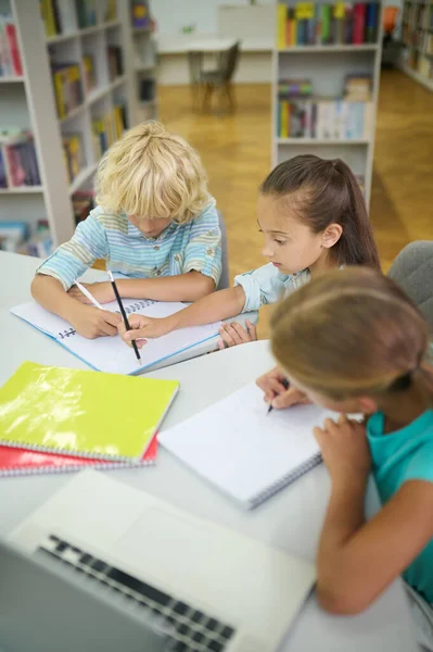 Girls and boy doing lessons in library — Foto Stock