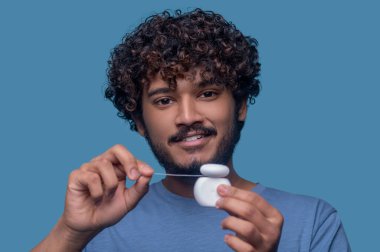 Diş ipi kullanmadan önce kameraya poz veren memnun adam.