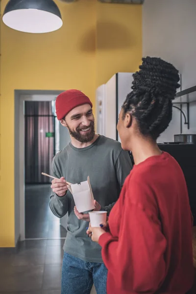 Tipo con fideos y chica con café de comunicación — Foto de Stock