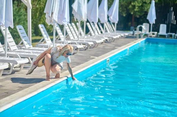 Belle femme blonde essayant l'eau dans la piscine — Photo