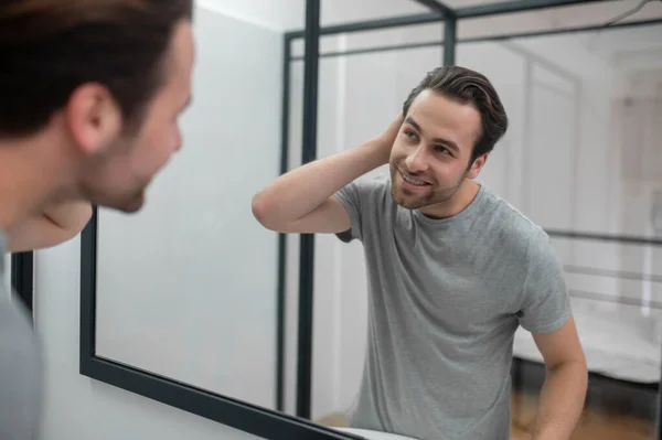 Een man bij de spiegel die zichzelf onderzoekt. — Stockfoto