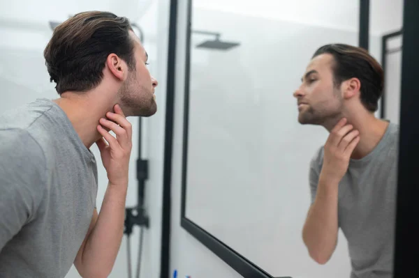 Человек рядом с зеркалом изучает себя — стоковое фото