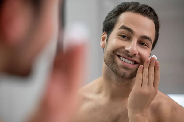 Halfnaakte man die bij de spiegel staat en scheerschuim op zijn gezicht aanbrengt — Stockfoto