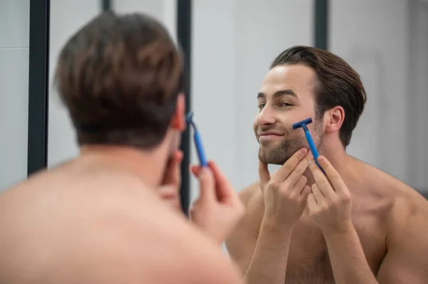 Молодой человек бреется перед зеркалом — стоковое фото