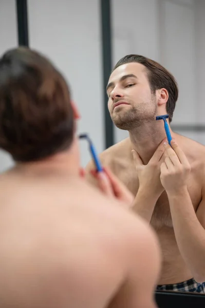 在镜子刮胡子的年轻人 — 图库照片