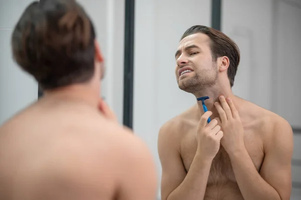 Νεαρός άνδρας ξυρίζεται και φαίνεται συγκεντρωμένος — Φωτογραφία Αρχείου