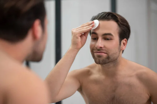 Schöner Mann reinigt sein Gesicht mit einem Schwamm — Stockfoto