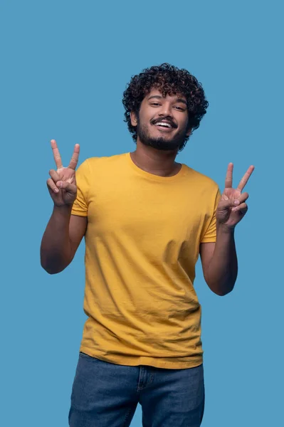 Smiling contented man showing a V-sign gesture — Fotografia de Stock