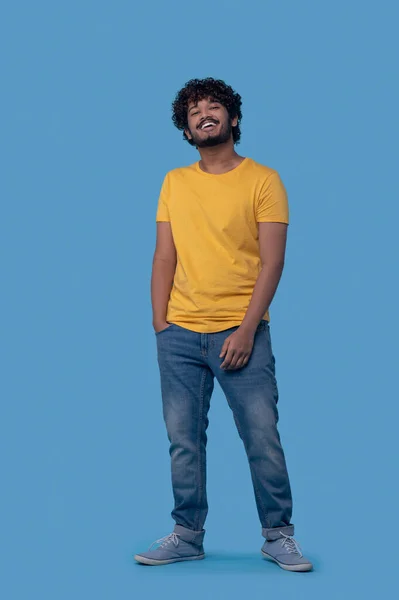 Killen med ett strålande leende poserar mot den blå bakgrunden — Stockfoto
