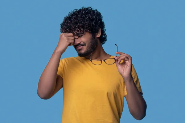 Tired curly-haired bearded guy suffering from eyestrain — Stockfoto