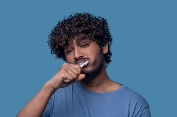 Displeased Indian guy performing a tooth-brushing procedure — Fotografia de Stock