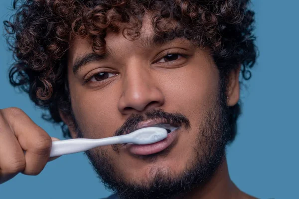 Klidný pohledný muž provádějící čištění zubů — Stock fotografie