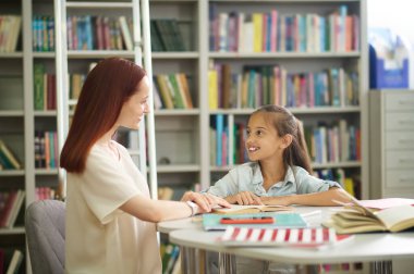 Gülümseyen kız ve kadın masada oturuyor.