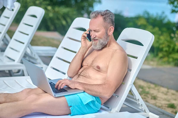 Bearded man working on a beach and having a phone call — Fotografia de Stock