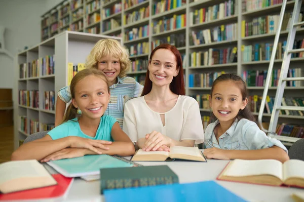 Frau mit Kindern lächelt in Bibliothek in die Kamera — Stockfoto