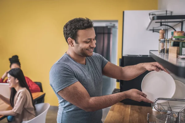 Guy stacking clean plates in office kitchen — Stockfoto