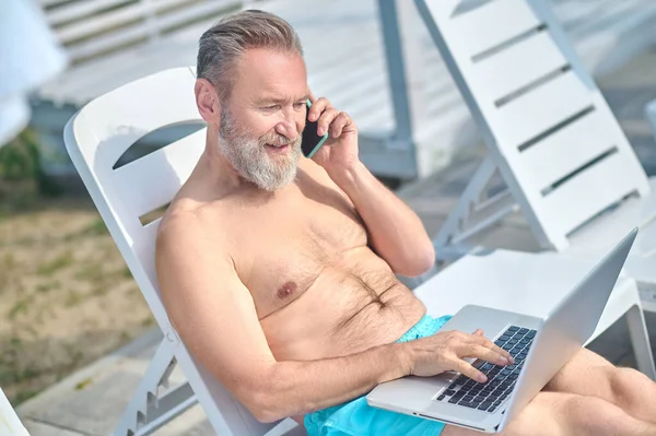 Bearded man working on a beach and having a phone call — Fotografia de Stock