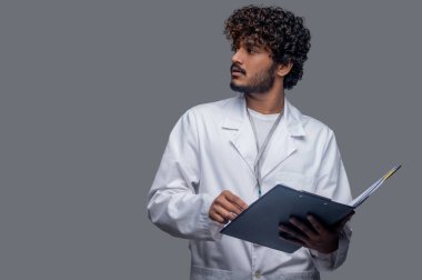 Belgeleri başka yöne bakan düşünceli yakışıklı bir pratisyen.