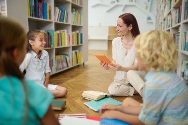 Tabletli bir kadın ve konuşan bir kızı dinleyen çocuklar.