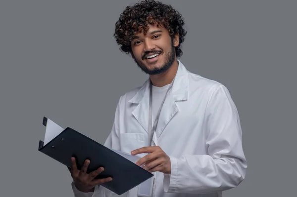 Dokter ceria dengan dokumen di tangannya melihat ke depan — Stok Foto
