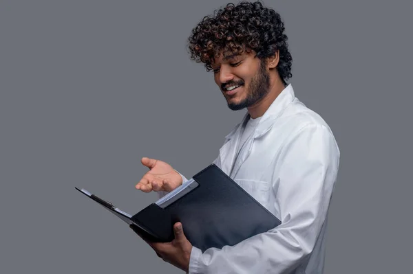 Tersenyum dokter meneliti dokumen di tangannya — Stok Foto