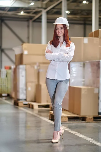 Woman with folded arms on chest standing in warehouse — Zdjęcie stockowe