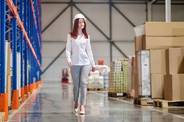 Woman in safety helmet walking on warehouse — Zdjęcie stockowe