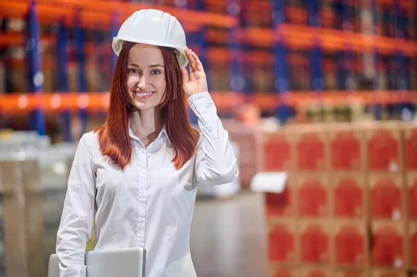 Vrouw met laptop aanraking met hand tot helm op hoofd — Stockfoto