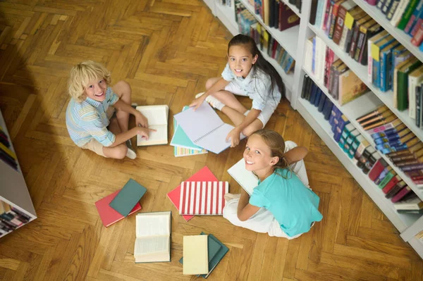 Children sitting on floor of library looking at camera — 图库照片