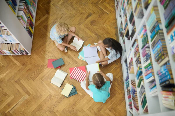 Vista superior de los niños estudiando en el suelo en la biblioteca —  Fotos de Stock