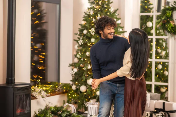 Мужчина танцует с женщиной в помещении с рождественскими украшениями — стоковое фото