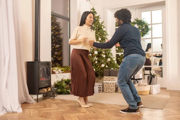 Женщина смотрит, как мужчина танцует возле рождественского дерева в помещении — стоковое фото