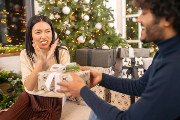 Счастливая женщина смотрит на мужчину с подарком — стоковое фото